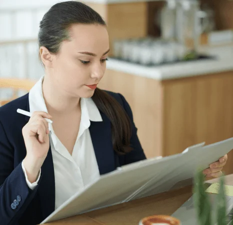 A translator proofreads a deadline submission packet as urgent translation services verify names, dates, and stamps.