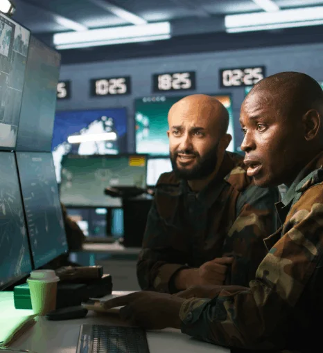 Officers review a NATO map room display while defence translation provide translations of military reports for clarity.