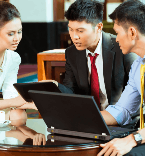 A business team reviews a Malaysia market plan, using Malay translation services to localize product and contract files.