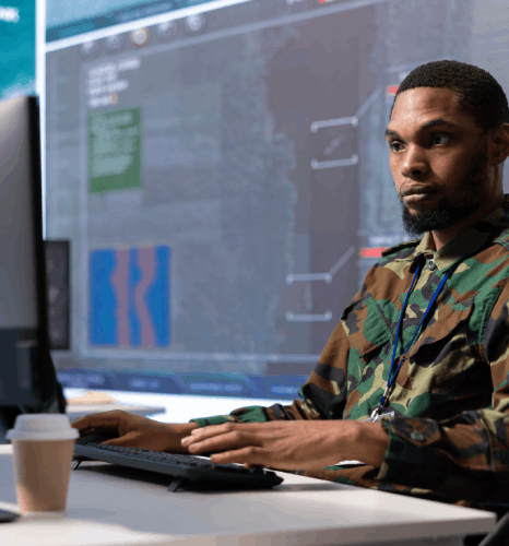 A linguist checks mission orders on a secure laptop, showing Military Translation Services for mission-critical ops.