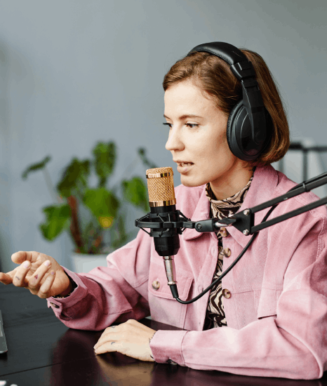 A narrator records E-learning Voiceover Services in a studio-quality booth while an engineer monitors clean levels.