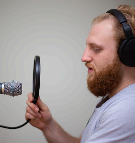 A voice artist records studio-ready audio in a booth, delivering German Voice Over Services with clear, natural tone.