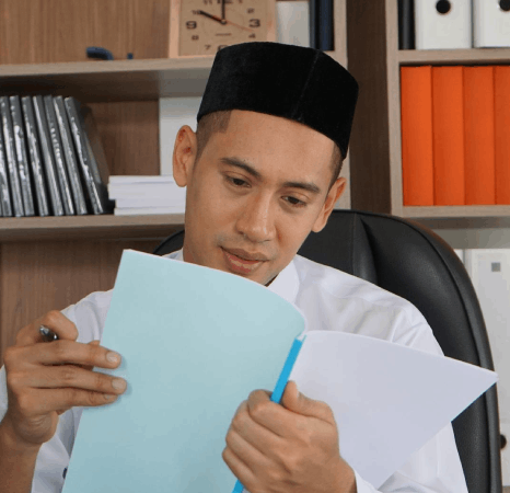A lecturer checks a syllabus and reading list, using Malay translation services to preserve citations and academic terms.