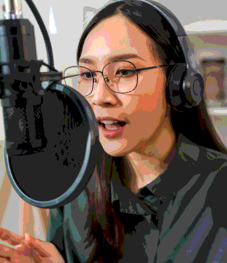 A voice artist reads a script beside a laptop, recording Tagalog Voice Over Services for audio and video projects.