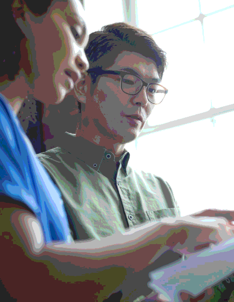 A technician compares a machine diagram to Lao instructions as Laotian Translation Services clarify setup steps.