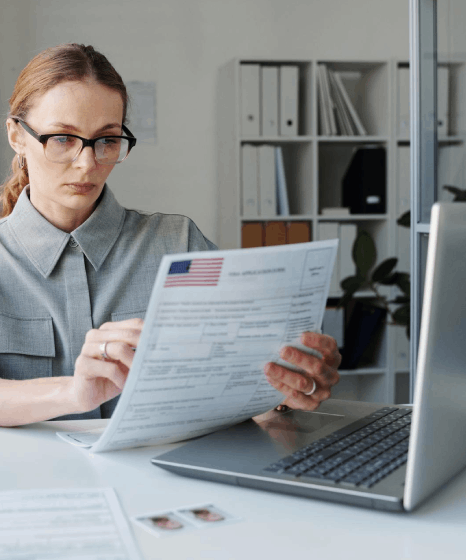 A translator compares a Finnish birth certificate to an English draft as Finnish translation services meet USCIS rules.