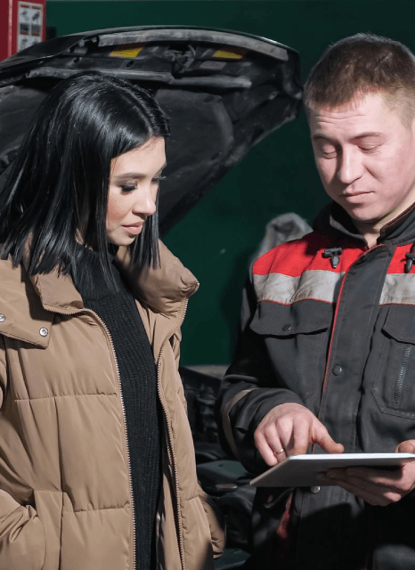 A technician checks a vehicle maintenance guide translation on a tablet, supported by automotive translation services.