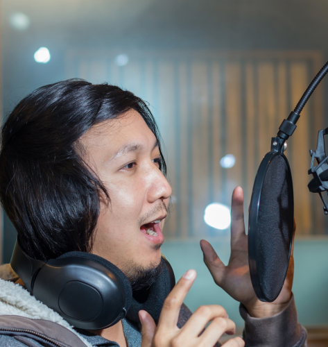 A native artist records Vietnamese Voice Over Services in a studio, checking levels for clear, native audio delivery.