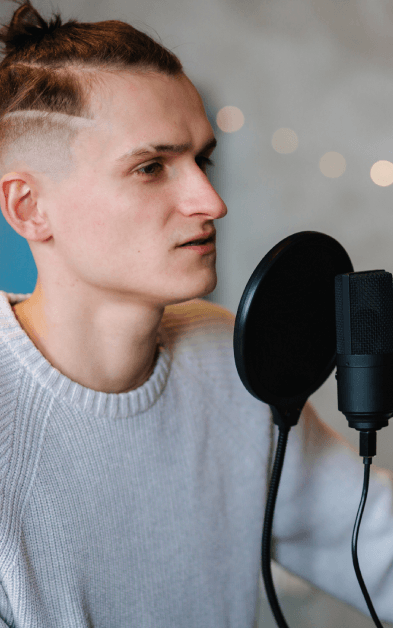 A deep voice actor records in a sound booth while the engineer monitors levels for Voice-Over Services on a new project.