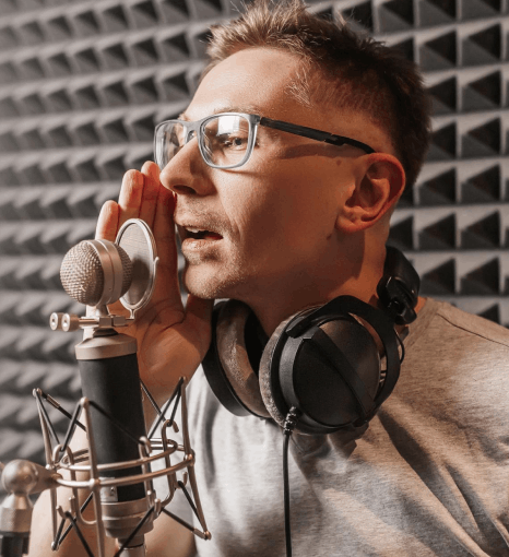 A voice actor records warm Voice Over Styles for every project, reading lines in a booth while tracking tone notes.