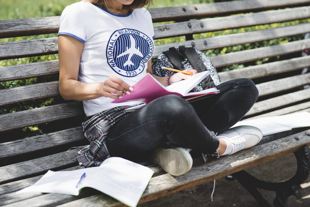 Girl sitting on bench in park studying