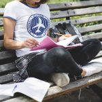 Girl sitting on bench in park studying