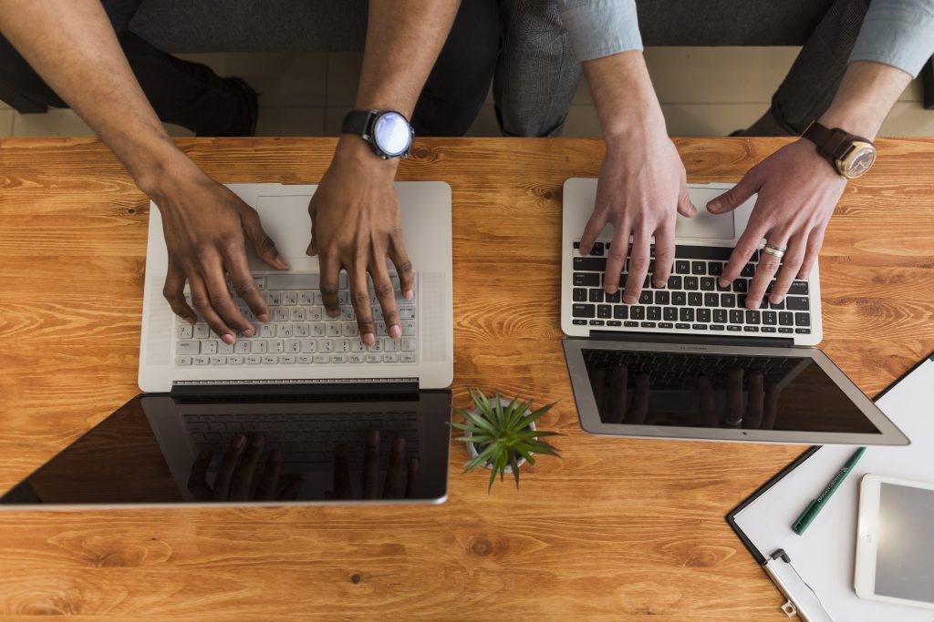 Crop hands browsing laptops