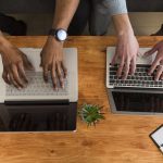 Crop hands browsing laptops