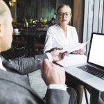 Two businesspeople working on document with laptop on desk