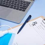 Doctor workplace. Medical stethoscope, laptop, blank clipboard and pen on light blue surface. corona virus covid-19. stethoscope, eyeglasses and face mask. Top view, flat lay, copy space.