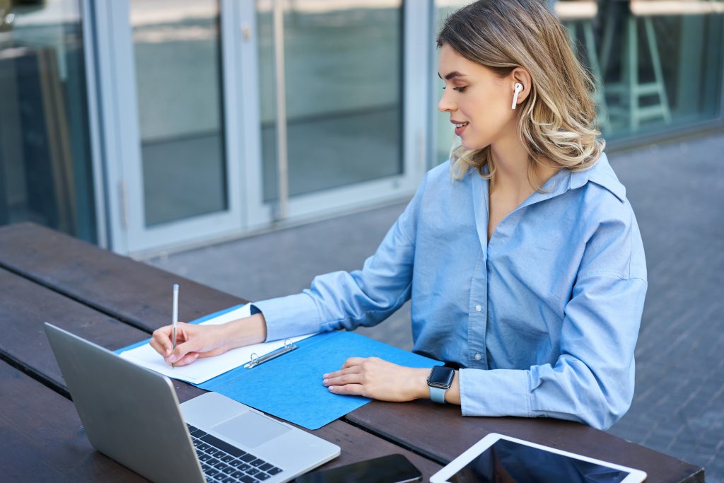 Portrait of young beautiful working woman works on remote with laptop student takes notes during onl