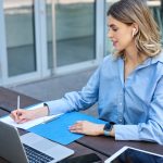 Portrait of young beautiful working woman works on remote with laptop student takes notes during onl