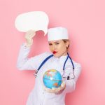 Front view young female doctor in white medical suit with blue stethoscope holding globe and white sign on the pink space medicine medical hospital health