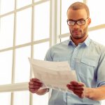 Worker carefully reading clear employee rights document while complex legal papers remain unreadable on desk